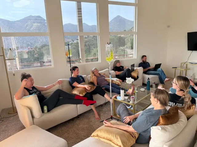 A group of clients relaxing on sofas in a living room while each receives a mobile IV drip