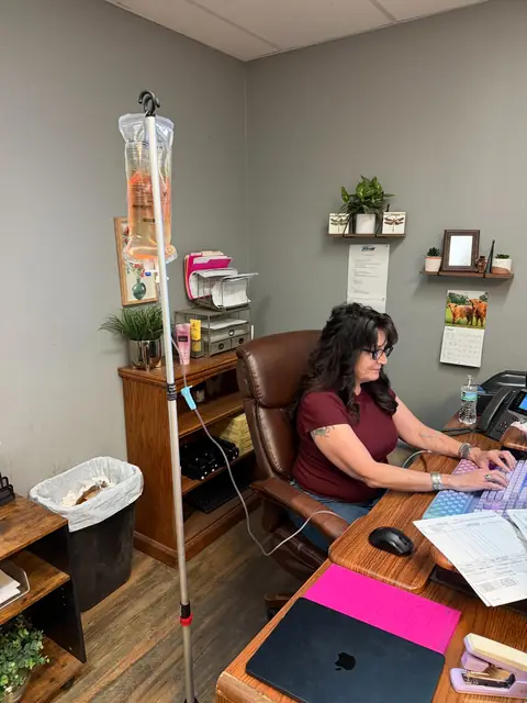 A woman working on a laptop at her office desk during a mobile IV session