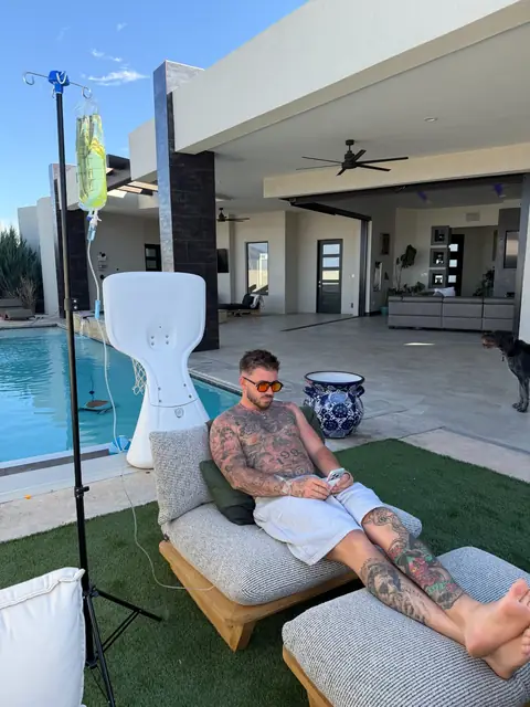 A client lounging poolside on a patio chair while receiving an IV drip